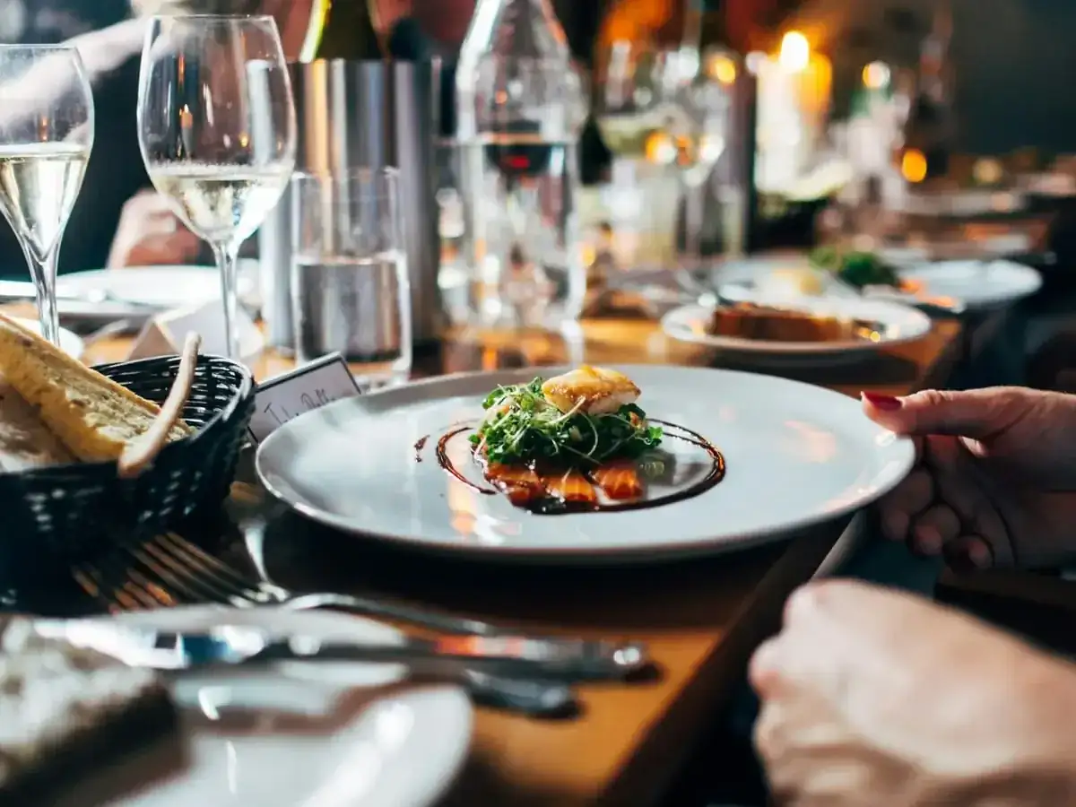 Mesa de restaurante de noche con un plato servido y copas de vino