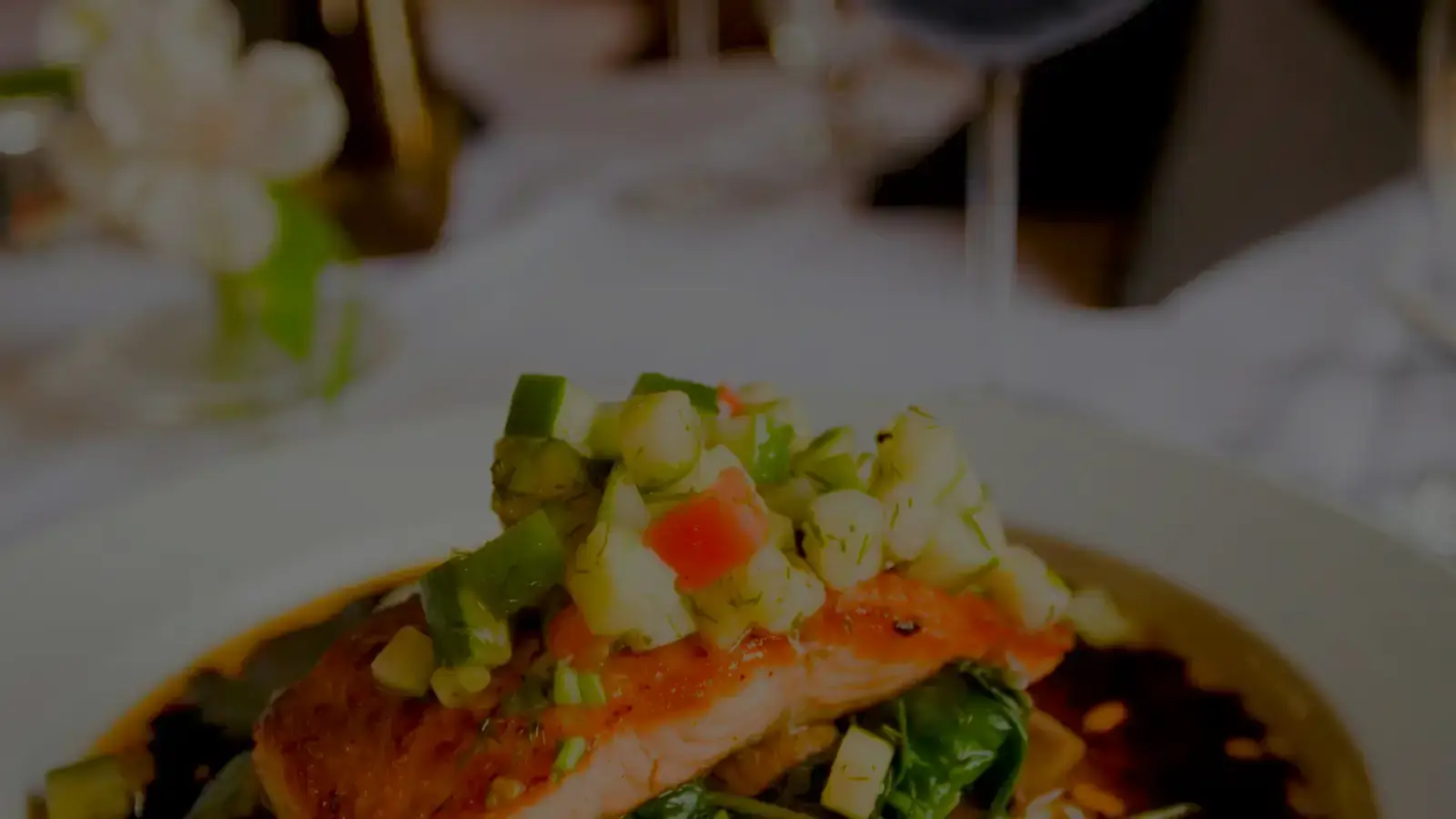 Primer plano de un plato de salmón a la plancha con una salsa de verduras, servido en un restaurante