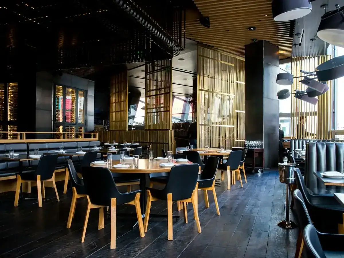 Interior de un restaurante vacío con mesas de madera y sillas oscuras