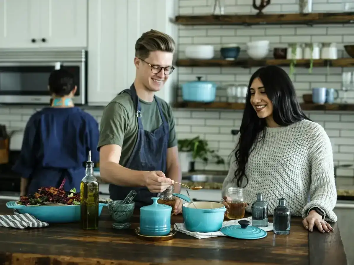 Tres personas trabajando juntas en una cocina alrededor de una mesa con platos y cuencos